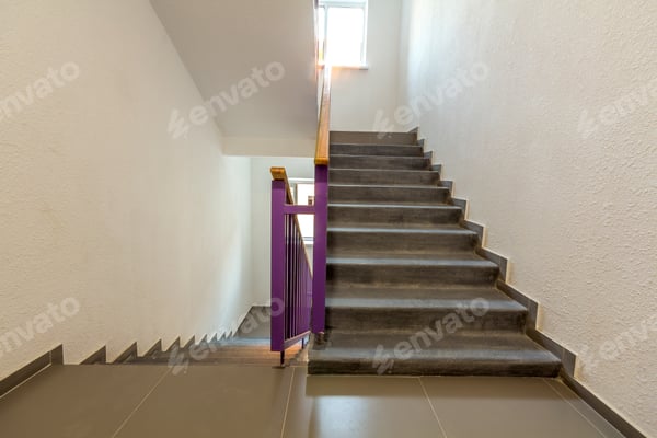 Schlichtes Treppenhaus mit Reinigungswagen und Warnaufsteller an der untersten Stufe